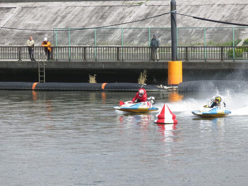 首都高速の下の道から見た江戸川競艇場の競争水面1マーク側を、選手たちが旋回するようす