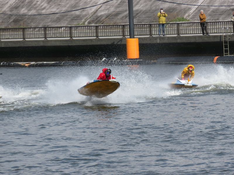 首都高速の下の道から見た江戸川競艇場の競争水面1マーク側を、選手たちが旋回するようす
